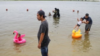 Pengunjung berwisata di Pantai Lagoon, Ancol Taman Impian, Jakarta, Minggu (26/5/2024). [Suara.com/Alfian Winanto]