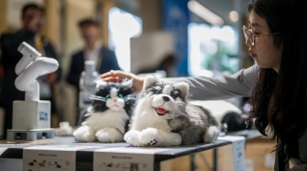 Pengunjung membelai hewan peliharaan menggunakan kecerdasan buatan di stan selama International Telecommunication Union (ITU) AI for Good Global Summit di Jenewa, Swiss, Kamis (30/5/2024). [Fabrice COFFRINI / AFP]