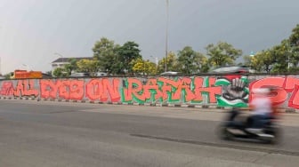 Pengendara melewati mural yang menggambarkan dukungan untuk warga Palestina di tembok pinggir tol lingkar luar Jakarta, Tanjung Barat, Jakarta Selatan, Senin (3/6/2024). [Suara.com/Alfian Winanto]