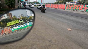 Pengendara melewati mural yang menggambarkan dukungan untuk warga Palestina di tembok pinggir tol lingkar luar Jakarta, Tanjung Barat, Jakarta Selatan, Senin (3/6/2024). [Suara.com/Alfian Winanto]