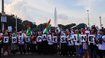 Massa mengangkat poster saat Aksi Bela Palestina di Kawasan Patung Kuda, Jakarta, Minggu (9/6/2024). [Suara.com/Alfian Winanto]