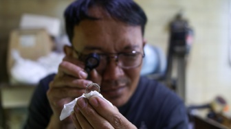 Perajin menyelesaikan pembuatan cincin di Metro Pasar Baru, Jakarta Pusat, Jumat (14/6/2024). [Suara.com/Alfian Winanto]