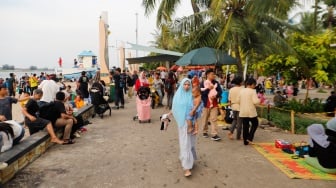 Pengunjung berwisata di Pantai Lagoon, Ancol Taman Impian, Jakarta, Selasa (18/6/2024). [Suara.com/Alfian Winanto]