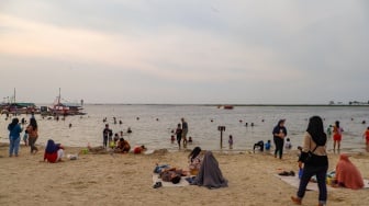 Pengunjung berwisata di Pantai Lagoon, Ancol Taman Impian, Jakarta, Selasa (18/6/2024). [Suara.com/Alfian Winanto]