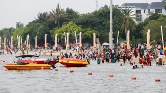 Pengunjung berwisata di Pantai Lagoon, Ancol Taman Impian, Jakarta, Selasa (18/6/2024). [Suara.com/Alfian Winanto]