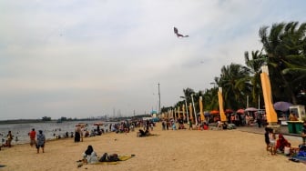 Pengunjung berwisata di Pantai Lagoon, Ancol Taman Impian, Jakarta, Selasa (18/6/2024). [Suara.com/Alfian Winanto]