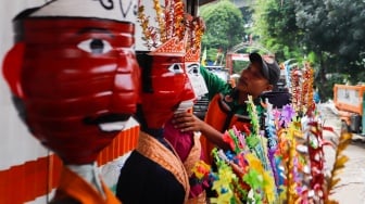 Petugas Unit Penanganan Sampah (UPS) Badan Air Dinas Lingkungan Hidup DKI Jakarta Kecamatan Jatinegara membuat ondel-ondel mini dari galon air minum bekas di Jakarta, Selasa (25/6/2024). [Suara.con/Alfian Winanto]