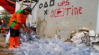 Petugas Unit Penanganan Sampah (UPS) Badan Air Dinas Lingkungan Hidup DKI Jakarta Kecamatan Jatinegara memilih galon bekas untuk dibuat ondel-ondel mini dari galon air minum bekas di Jakarta, Selasa (25/6/2024). [Suara.con/Alfian Winanto]