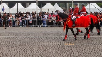 Warga menonton pertunjukan defile pasukan berkuda saat upacara peringatan HUT ke-78 Bhayangkara di Lapangan Silang Monas, Jakarta, Senin (1/7/2024). [Suara.com/Alfian Winanto]