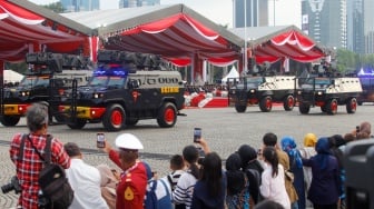 Warga menonton pertunjukan defile kendaraan saat upacara peringatan HUT ke-78 Bhayangkara di Lapangan Silang Monas, Jakarta, Senin (1/7/2024). [Suara.com/Alfian Winanto]