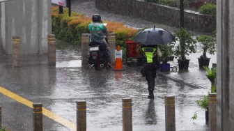 Warga berjalan saat menggunakan payung saat hujan lebat di Jalan Gatot Subroto, Jakarta, Selasa (2/7/2023). [Suara.com/Alfian Winanto]