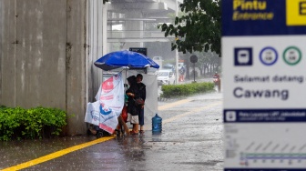 Warga berteduh saat hujan lebat di Jalan Gatot Subroto, Jakarta, Selasa (2/7/2023). [Suara.com/Alfian Winanto]