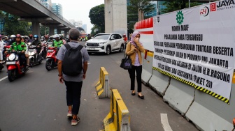 Sejumlah pejalan kaki melintas disamping proyek galian di Jl Rasuna Said, Jakarta, Rabu (10/7/2024). [Suara.com/Alfian Winanto]