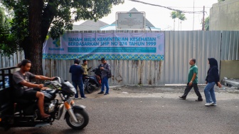 Warga melintas di depan Kantor Perkumpulan Keluarga Berencana Indonesia {PKBI) yang sudah dikosongkan dan ditutupi seng di Jakarta, Kamis (11/7/2024). [Suara.com/Alfian Winanto]