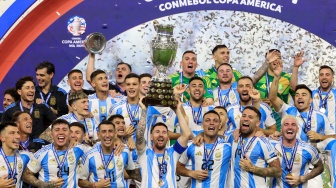 Penyerang Argentina Lionel Messi berselebrasi mengangkat trofi bersama para pemain Timnas Argentin usai pertandingan sepak bola final Copa America 2024 antara Argentina dan Kolombia di Stadion Hard Rock, di Miami, Florida, Minggu (14/7/2024). [CHARLY TRIBALLEAU / AFP]