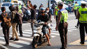 Sejumlah petugas kepolisian memberikan himbauan kepada pengendara yang melanggar peraturan saat Operasi Patuh Jaya 2024 di Jalan Letjen S Parman, Jakarta, Senin (15/07/2024). [Suara.com/Alfian Winanto]