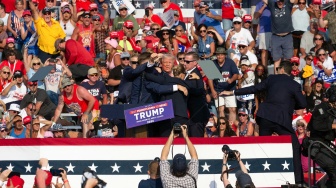 Kandidat Partai Republik dan mantan Presiden AS Donald Trump terlihat dengan wajah berlumuran darah dikelilingi oleh agen Secret Service dan dibawa turun dari panggung usai insiden penembakan pada acara kampanye di Butler Farm Show Inc. di Butler, Pennsylvania, Sabtu (13/7/2024). [Rebecca DROKE/AFP]