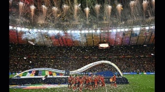 Para pemain Spanyol berselelebrasi sambil memegang trofi setelah memenangkan pertandingan sepak bola Final Euro 2024 antara Spanyol dan Inggris di Olympiastadion, Berlin, Jerman, Minggu (14/7/2024). [JAVIER SORIANO / AFP]