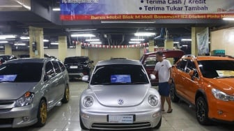 Pengunjung melihat mobil bekas yang dijual di bursa mobil bekas Blok M, Jakarta, Jumat (19/7/2024). [Suara.com/Alfian Winanto]