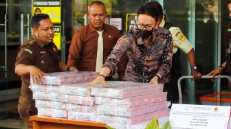 Petugas Kejaksaan menampilkan barang bukti berupa uang tunai dan tas mewah milik tersangka kasus dugaan korupsi di PT Timah Harvey Moeis dan Helena Lim di Kejaksaan Negeri Jakarta Selatan, Senin (22/7/2024). [Suara.com/Alfian Winanto]