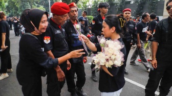 Massa dari unsur badan dan sayap pusat Partai Demokrasi Indonesia Perjuangan (PDIP) membagikan bunga saat menggelar aksi di depan gedung Komnas HAM di Jakarta, Jumat (27/7/2024). [Suara.com/Alfian Winanto]