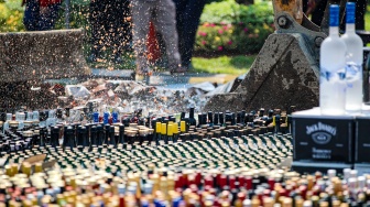 Petugas melakukan pemusnahan minuman keras ilegal hasil penindakan di Kantor Pusat Bea Cukai, Jakarta, Rabu (31/7/2024). [Suara.com/Alfian Winanto]