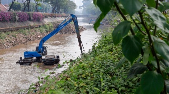 Pekerja menggunakan alat berat mengeruk lumpur endapan Kali Ciliwung di kawasan Manggarai, Jakarta, Kamis (8/8/2024). [Suara.com/Alfian Winanto]