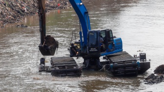 Pekerja menggunakan alat berat mengeruk lumpur endapan Kali Ciliwung di kawasan Manggarai, Jakarta, Kamis (8/8/2024). [Suara.com/Alfian Winanto]