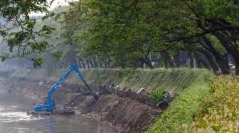 Pekerja menggunakan alat berat mengeruk lumpur endapan Kali Ciliwung di kawasan Manggarai, Jakarta, Kamis (8/8/2024). [Suara.com/Alfian Winanto]