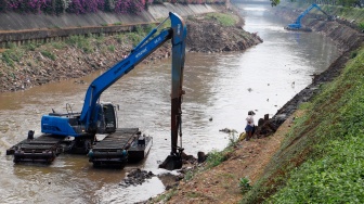 Pekerja menggunakan alat berat mengeruk lumpur endapan Kali Ciliwung di kawasan Manggarai, Jakarta, Kamis (8/8/2024). [Suara.com/Alfian Winanto]