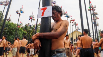 Peserta berdua mengikuti lomba panjat pinang di Pantai Festival, Taman Impian Jaya Ancol, Jakarta, Sabtu (17/8/2024). [Suara.com/Alfian Winanto]