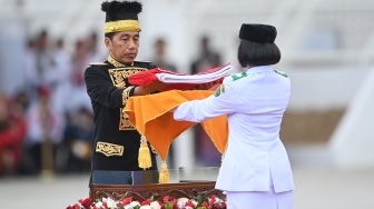 Presiden Joko Widodo (kiri) menyerahkan duplikat Bendera Pusaka kepada anggota Paskibraka 2024 asal Kalimantan Timur Livenia Evelyn Kurniawan (kanan) untuk dikibarkan dalam upacara Peringatan Detik-detik Proklamasi Kemerdekaan Republik Indonesia (RI) di lapangan upacara Istana Negara Ibu Kota Nusantara (IKN), Penajam Paser Utara, Kalimantan Timur, Sabtu (17/8/2024). [ANTARA FOTO/Hafidz Mubarak A/app/wpa]