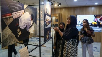 Pengunjung melihat karya foto yang dipamerkan pada pameran foto Rekam Jakarta di Perpustakaan Jakarta Galeri PDS HB Jassin, Taman Ismail Marzuki (TIM), Jakarta, Sabtu (24/08/2024). [Suara.com/Alfian Winanto]