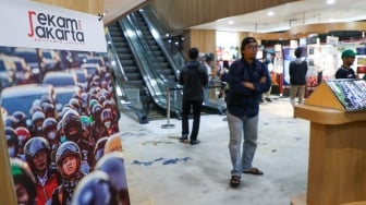 Pengunjung melihat karya foto yang dipamerkan pada pameran foto Rekam Jakarta di Perpustakaan Jakarta Galeri PDS HB Jassin, Taman Ismail Marzuki (TIM), Jakarta, Sabtu (24/08/2024). [Suara.com/Alfian Winanto]