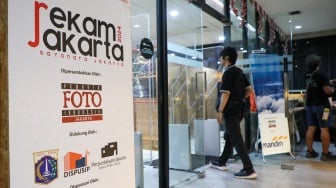 Pengunjung melihat karya foto yang dipamerkan pada pameran foto Rekam Jakarta di Perpustakaan Jakarta Galeri PDS HB Jassin, Taman Ismail Marzuki (TIM), Jakarta, Sabtu (24/08/2024). [Suara.com/Alfian Winanto]