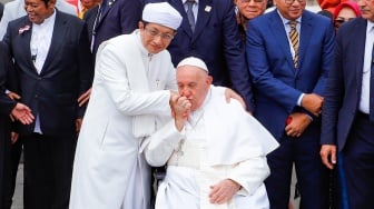 Pemimpin Takhta Suci Vatikan Paus Fransiskus (kanan) mencium tangan Imam Besar Masjid Istiqlal Nasaruddin Umar usai melakukan foto bersama di Masjid Istiqlal, Jakarta, Kamis (5/9/2024). [Suara.com/Alfian Winanto]