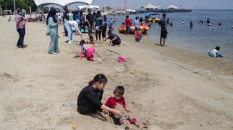 Pengunjung bermain air di Pantai Lagoon, Ancol Taman Impian, Jakarta, Senin (16/9/2024). [Suara.com/Alfian Winanto]