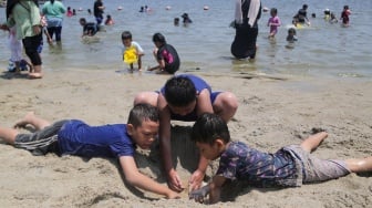 Pengunjung bermain air di Pantai Lagoon, Ancol Taman Impian, Jakarta, Senin (16/9/2024). [Suara.com/Alfian Winanto]