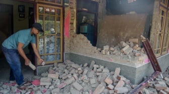 Warga membersihkan puing rumah yang runtuh pasca gempa bumi di Desa Cibeureum, Kertasari, Kabupaten Bandung, Jawa Barat, Rabu (18/9/2024). [ANTARA FOTO/Novrian Arbi/Spt]