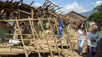 Warga melintas di dekat rumah yang rusak pasca gempa bumi di Desa Cibeureum, Kertasari, Kabupaten Bandung, Jawa Barat, Rabu (18/9/2024). [ANTARA FOTO/Novrian Arbi/Spt]
