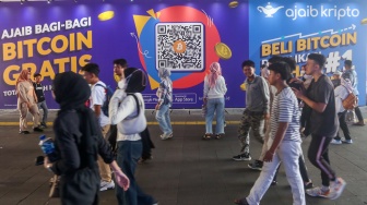 Warga melintas dengan latar iklan bitcoin di Terowongan Kendal, Jakarta, Selasa (24/9/2024). [Suara.com/Alfian Winanto]