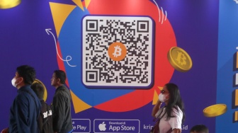 Warga melintas dengan latar iklan bitcoin di Terowongan Kendal, Jakarta, Selasa (24/9/2024). [Suara.com/Alfian Winanto]