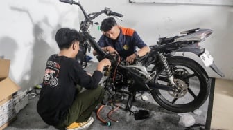 Teknisi mengonversi sepeda motor berbahan bakar minyak menjadi sepeda motor listrik di Bengkel Elders Garage, Jakarta, Jumat (4/10/2024). [Suara.com/Alfian Winanto]