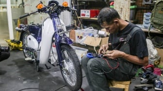 Teknisi mengonversi sepeda motor berbahan bakar minyak menjadi sepeda motor listrik di Bengkel Elders Garage, Jakarta, Jumat (4/10/2024). [Suara.com/Alfian Winanto]