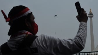 Warga memotret aksi pesawat tempur Sukhoi pada Peringatan HUT ke-79 TNI di kawasan Monas, Jakarta, Sabtu (5/10/2024) .[ANTARA FOTO/Indrianto Eko Suwarso]