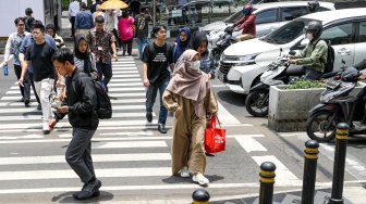 Warga beraktivitas saat fenomena hari tanpa bayangan di kawasan Bundaran Hotel Indonesia (HI), Jakarta, Selasa (8/10/2024). [Suara.com/Alfian Winanto]