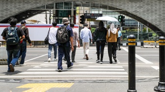 Warga beraktivitas saat fenomena hari tanpa bayangan di kawasan Bundaran Hotel Indonesia (HI), Jakarta, Selasa (8/10/2024). [Suara.com/Alfian Winanto]