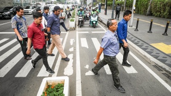 Warga beraktivitas saat fenomena hari tanpa bayangan di kawasan Bundaran Hotel Indonesia (HI), Jakarta, Selasa (8/10/2024). [Suara.com/Alfian Winanto]