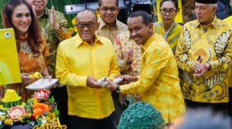 Ketua Umum Partai Golkar Bahlil Lahadalia (kanan) memberikan potongan tumpeng kepada Aburizal Bakri saat perayaan HUT ke-60 Partai Golkar di Kantor DPP Golkar, Jakarta, Senin (21/10/2024). [Suara.com/Alfian Winanto]