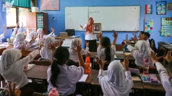 Guru memperlihatkan bingkai foto presiden Prabowo Subianto dan wakil presiden Gibran Rakabuming Raka kepada murid di SDN Pondok Labu 14 Pagi, Jakarta, Selasa (22/10/2024). [Suara.com/Alfian Winanto]